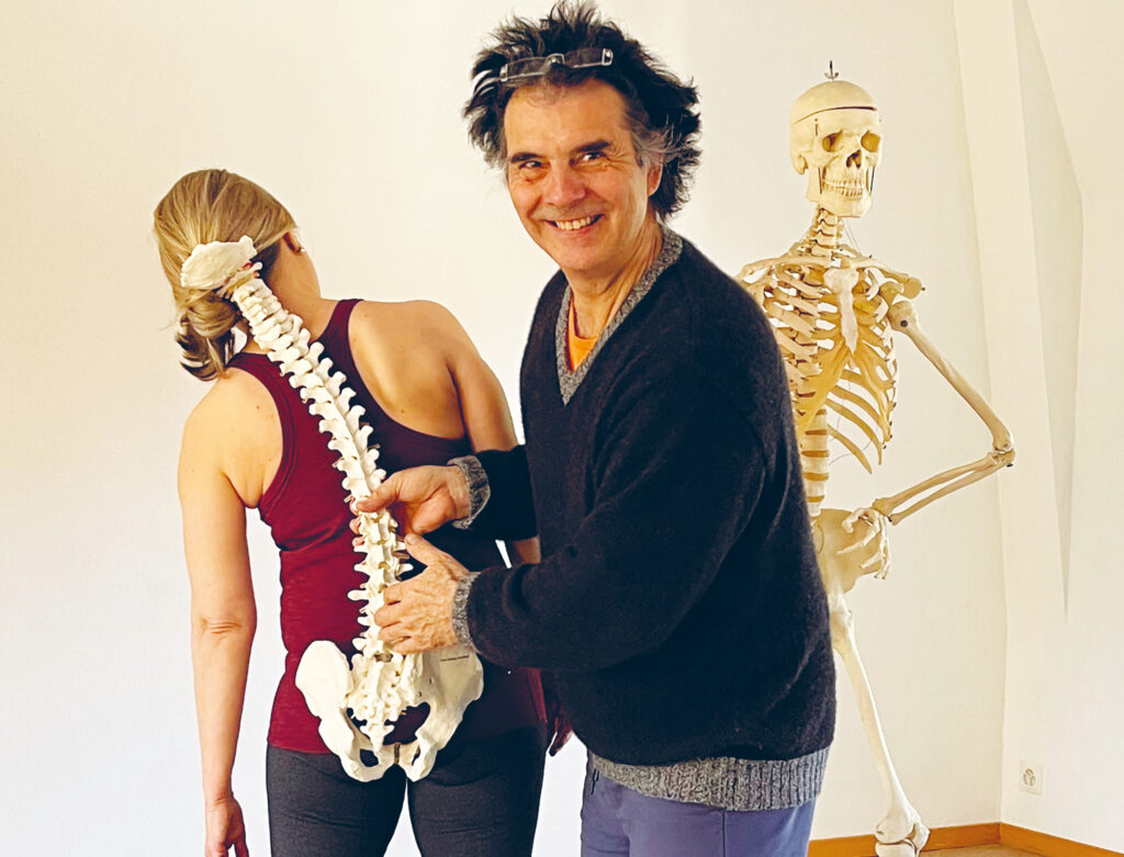 Hansjörg Straumann, Referent in der Yoga Therapie Ausbildung, veranschaulicht mit einem anatomisches Modell der Wirbelsäule die Krümmung der Wirbelsäule in einem Asana der Gruppe Seitbeuge.
