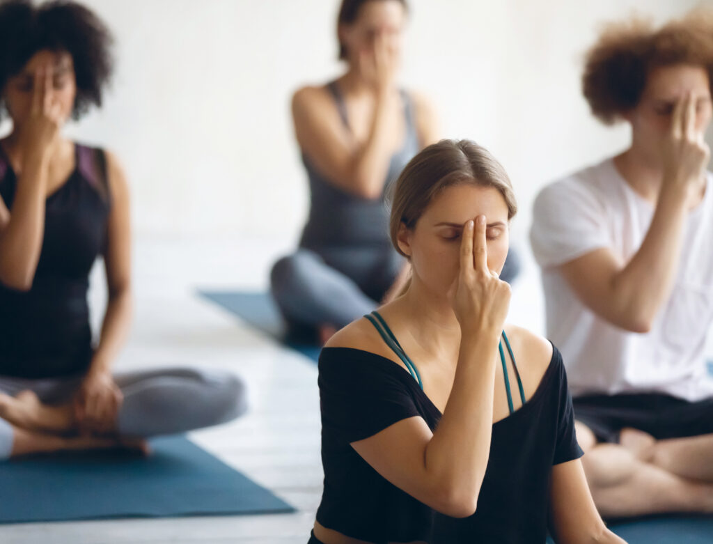 Yogaschülerinnen, die die Atemtechnik Nadishodhana üben, damit Prana in den Energiekanälen zirkulieren kann.