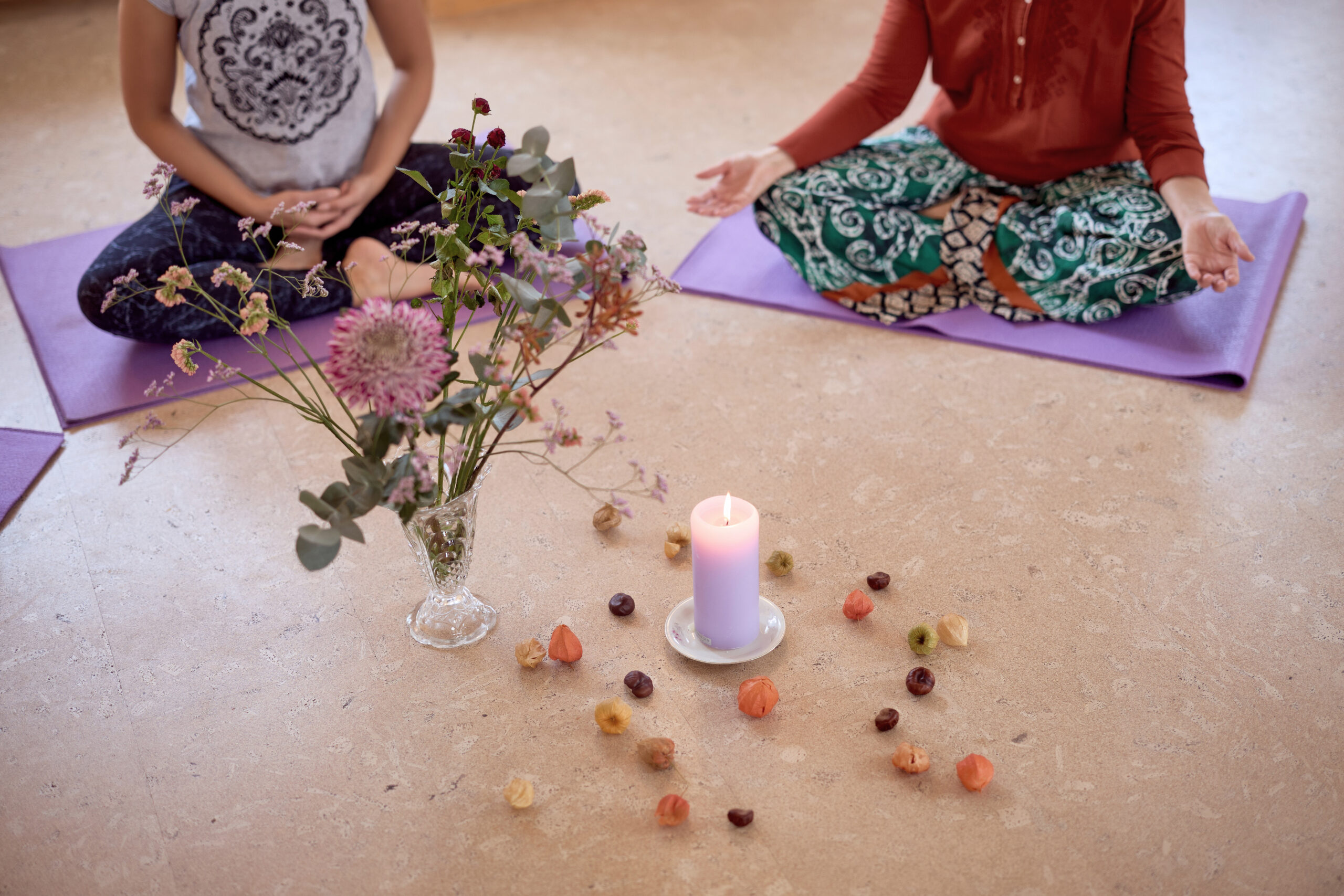 Zwei Yogapraktizierende üben Trataka, sich auf die Kerzenflamme konzentrieren.