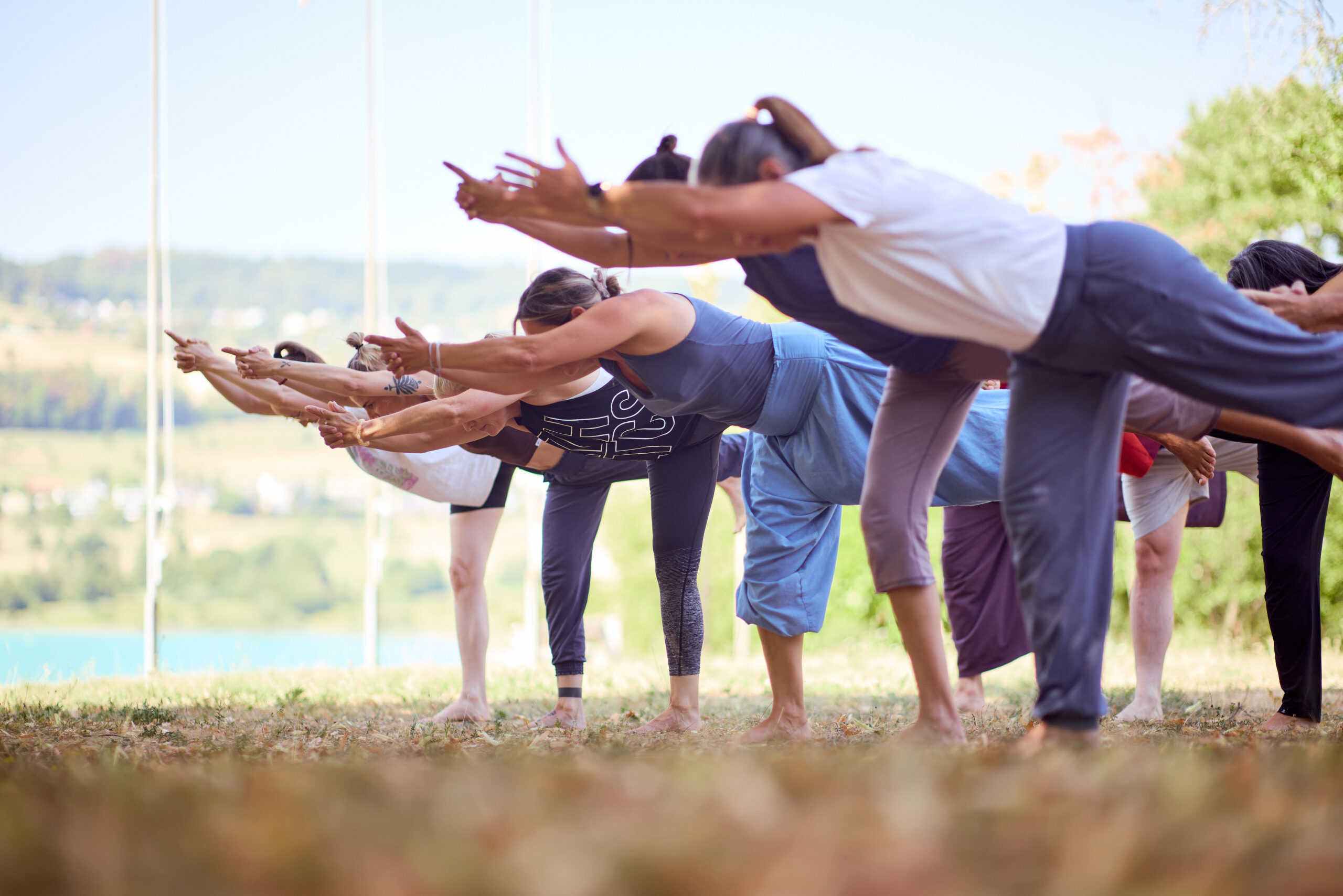 Studierende der Yoga-Ausbildung in der Haltgung Virabhadrasana im Freien.